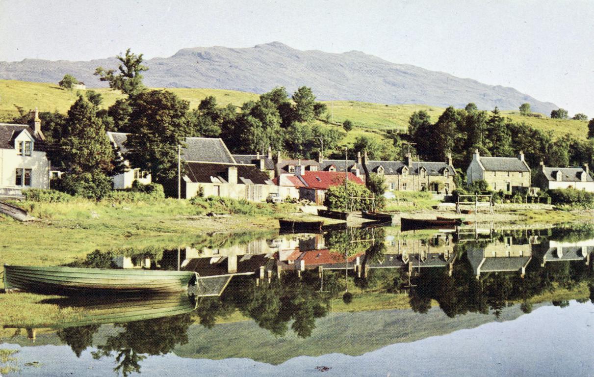 This photo, an early example of the coloured variety, shows a vibrant summer view of the small village of Lochcarron, nestled on the banks of the loch of the same name. A typically rugged mountain of the Highland north-west can be seen in the background.