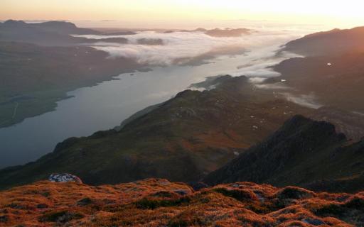 The rocky landscape surrounding Loch Maree from Slioch, basking in the sunset