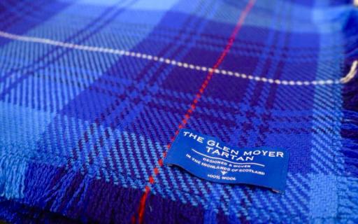 Close up image of Glen Moyer tartan - consisting of shades of light and dark blue with a single thread of red running through the cloth