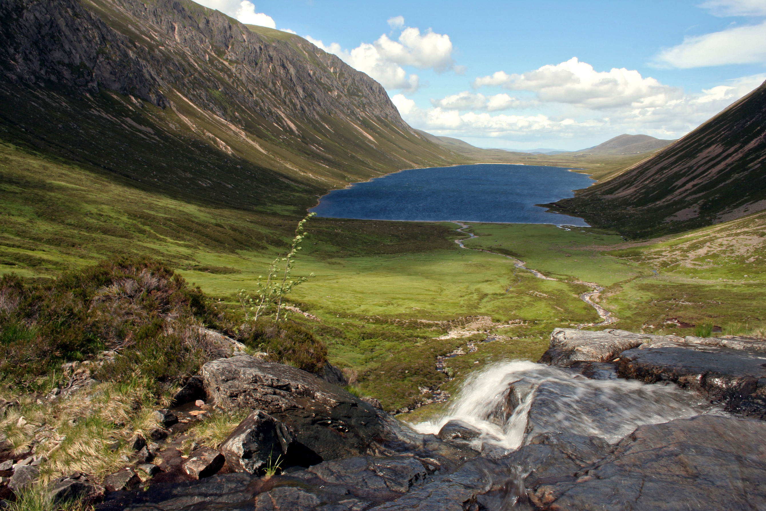 Overlooking a steep sloping drop into a coire. Loch Einich can be seen within this coire, in the top 50% of the image.