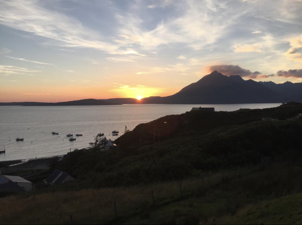 Looking out of the sun setting on the Isle of Skye. Boats are sailing on the water to the east