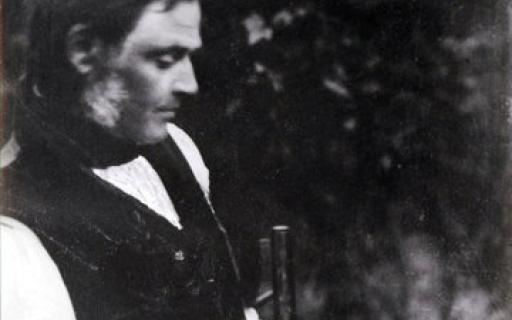 Robert Dick in a black buttoned vest looking at leaf prints