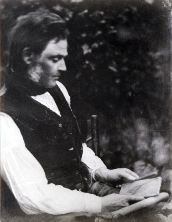 Robert Dick in a black buttoned vest looking at leaf prints