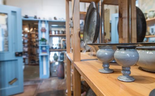 A pottery workshop display with clay cups and plates in grey.