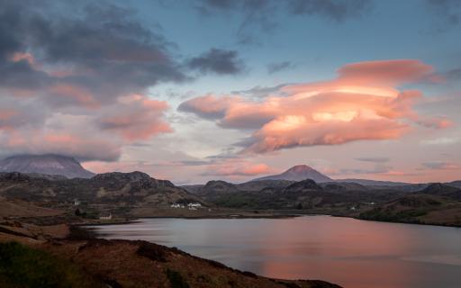 The cloudy blue and pink sky above the rocky landscape of Ben Stack. A large loch is visible in the landscape, in the bottom half of the image