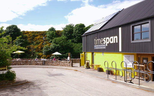Contemporary building with dark grey roof and yellow sides the site of Timespan museum.