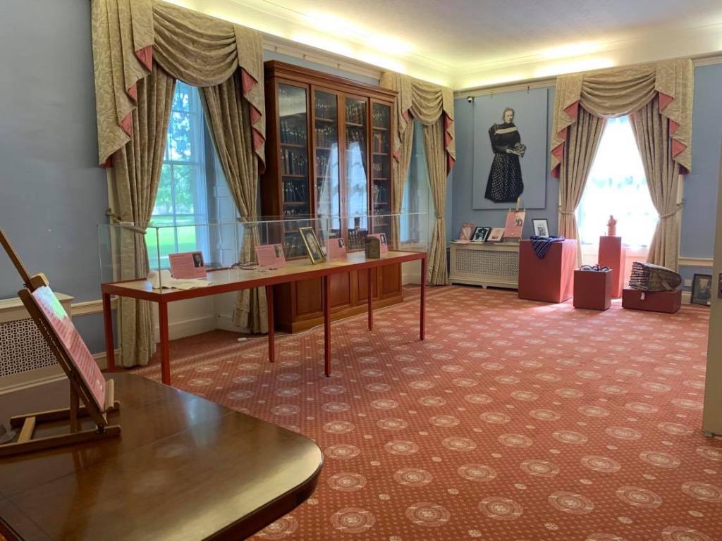 An exhibition room in Nairn Museum. There are exhibits incased in glass boxes with pink information panels which feature prominently in the room.