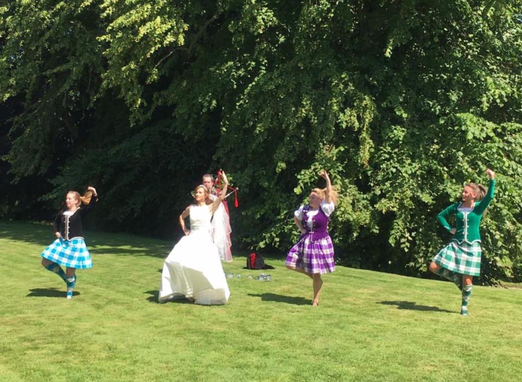 Women in Highland dancing dresses and a bride in a wedding dress taking part in Highland dancing
