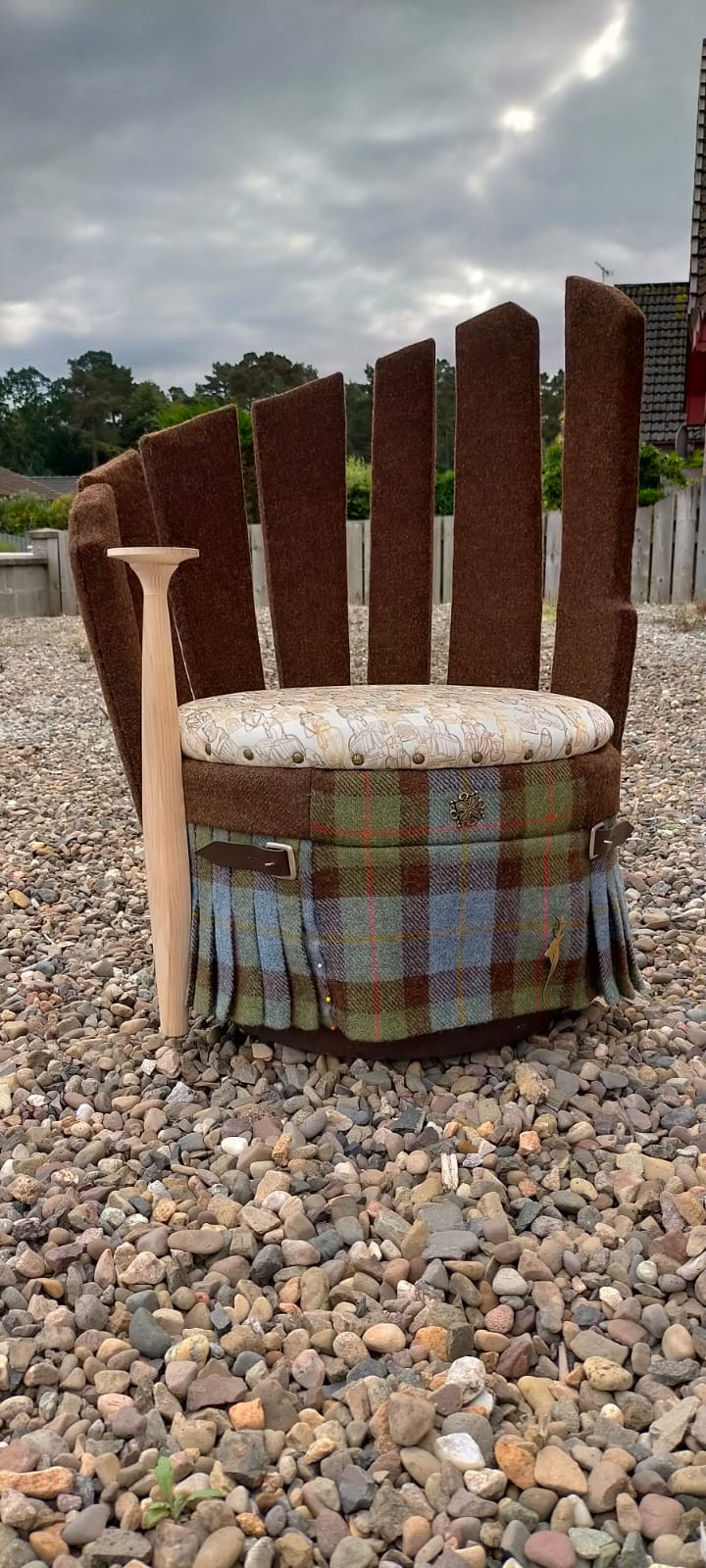 A chair with large fabric staves, a cushion with imprints of the Lewis Chessman in shades of orange and brown, and a base covered with Harris Tweed.