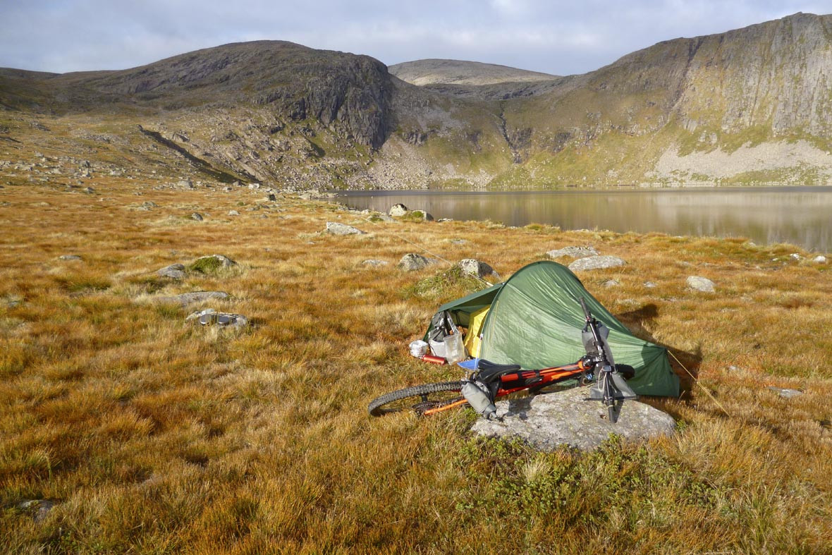 A green tent pitched by the shore of Loch Etchachan